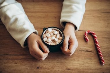 Bir adam evde, mutfak masasında marşmelovlu kakao içiyor. Tatil atmosferi. Kış havası, tatil evi istirahatı.