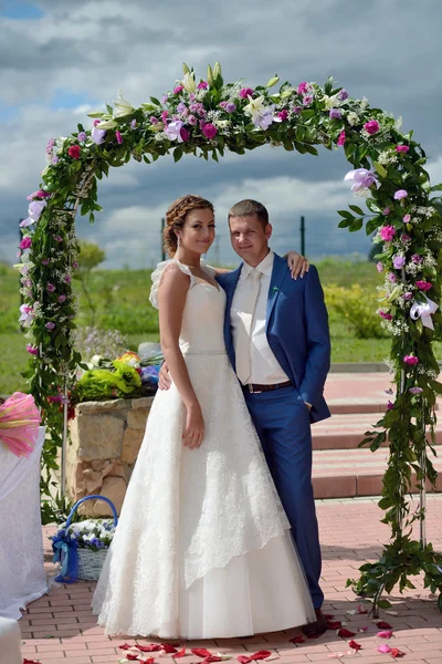 Bella sposa con sposo vicino arco di nozze — Foto Stock