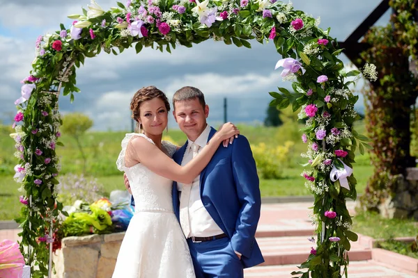 Bella sposa con sposo vicino arco di nozze — Foto Stock