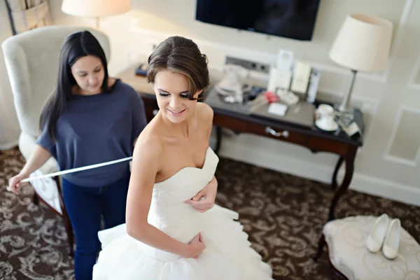 Bridesmaid lacing wedding dress for bride — Stock Photo, Image