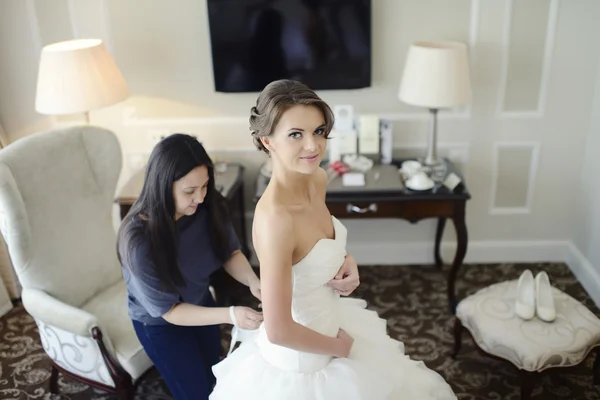 Bridesmaid lacing wedding dress for bride — Stock Photo, Image