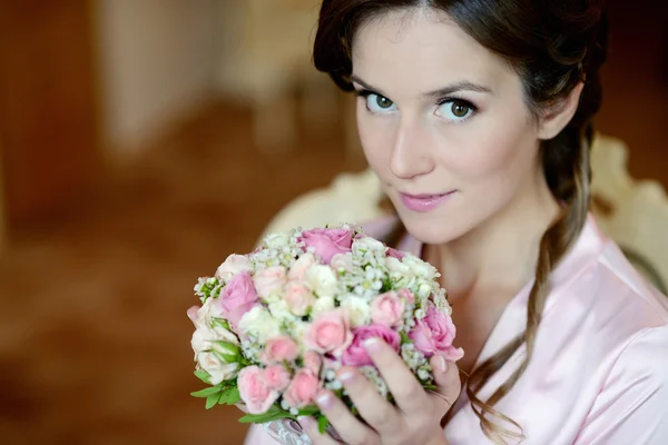 Bride in dressing gown with bouquet — Stock Photo, Image