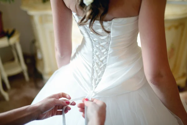 Bridesmaid lacing wedding dress for bride — Stock Photo, Image