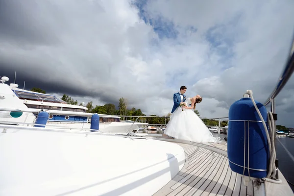 Bröllopsparet kramas på yacht Stockbild