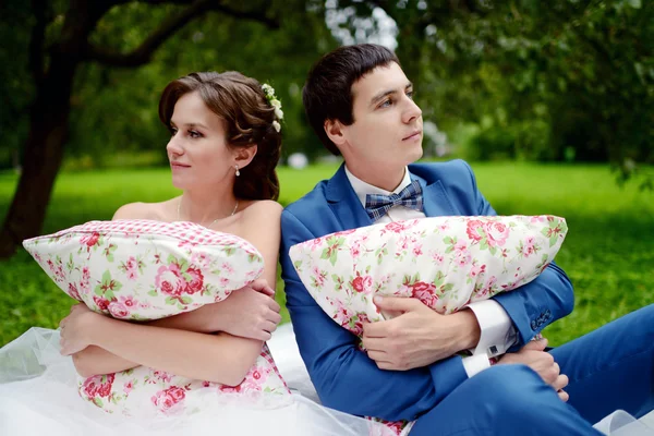 Para ślub w parku trzymając poduszki — Zdjęcie stockowe