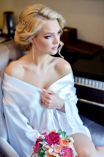 Bride in dressing gown with bouquet — Stock Photo, Image