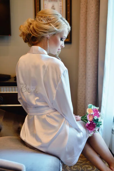 Bride in dressing gown with bouquet — Stock Photo, Image