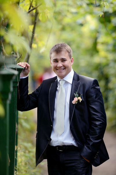 Handsome groom in suit in park