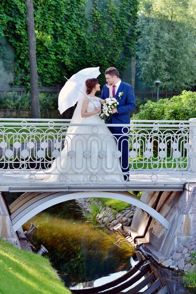 Hochzeitspaar umarmt sich auf Brücke — Stockfoto