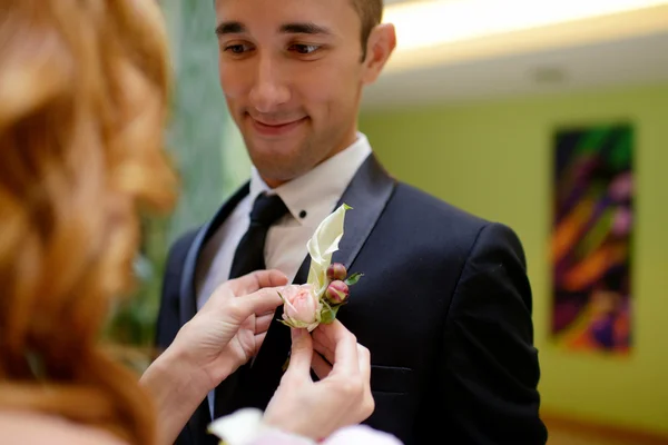 Bruden bär boutonniere på brudgummen — Stockfoto