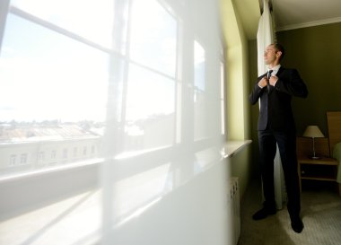 Takım elbise ayakta pencerede damat