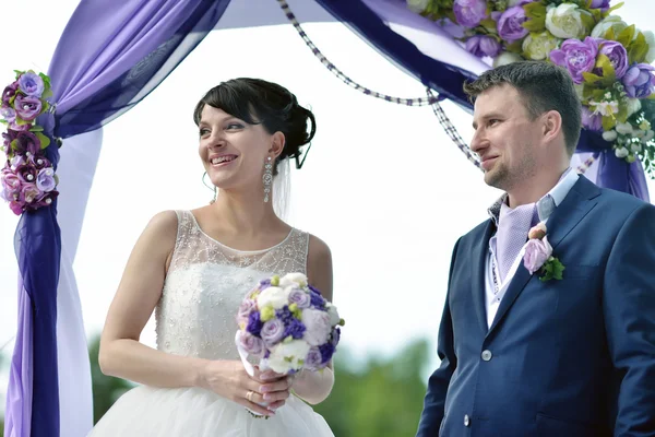 Невеста с женихом на свадебной арке — стоковое фото