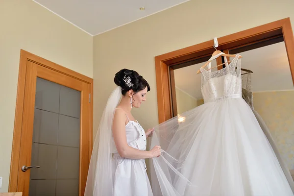 Vackra brud tittar på bröllopsklänning — Stockfoto