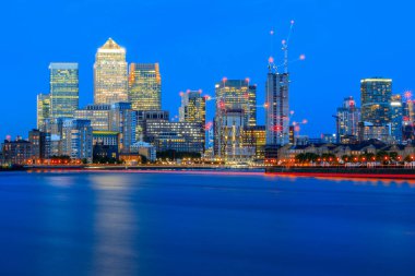 Londra 'nın doğusunda büyük bir iş bölgesi olan Canary Wharf' ta uzun süre açık alan, aydınlatılmış şehir manzarası.