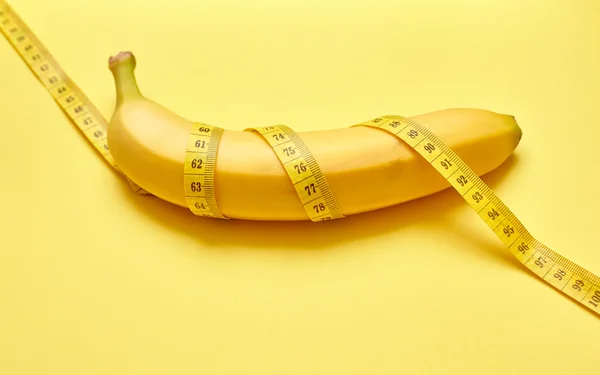 Изолированный банан с измерительной лентой на желтом фоне — стоковое фото