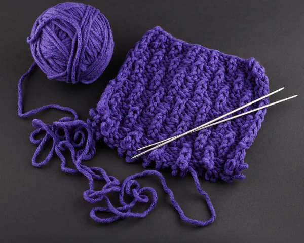 A piece of purple knitting, against a dark background — Stock Photo, Image