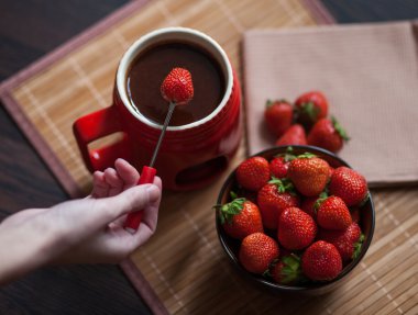 Tatlı. Olgun, parlak çilek ahşap arka plan üzerinde kırmızı bir fincan çikolata fondü