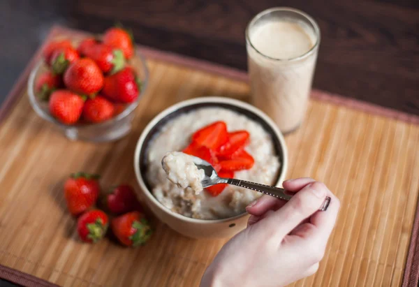 Горячая овсянка с кусочками клубники и теплого какао с молоком на деревянном столе — стоковое фото