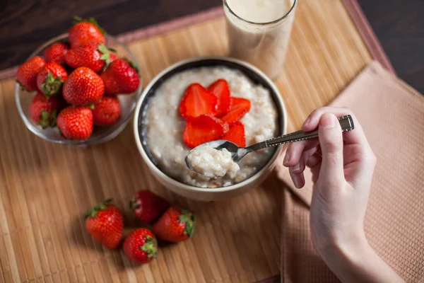 Hot oatmeal, with pieces of strawberries and warm cocoa with milk on a wooden table — Stock Photo, Image