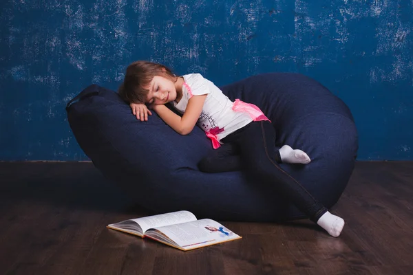 Mobili imbottiti. Un bambino con giocattoli e libri su una borsa della sedia — Foto Stock