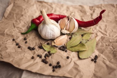 Biber biber, kara biber bezelye, defne yaprağı ve sarımsak. Taze ve kurutulmuş baharat kraft kağıt üzerinde. Yemek pişirmek için malzemeler