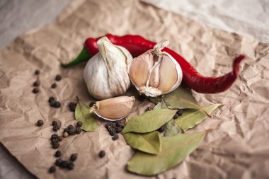 Biber biber, kara biber bezelye, defne yaprağı ve sarımsak. Taze ve kurutulmuş baharat kraft kağıt üzerinde. Yemek pişirmek için malzemeler