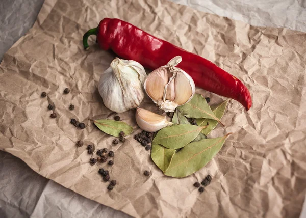 Chili pepper, black pepper peas, bay leaf and garlic. Fresh and Dried spices on kraft paper. Ingredients for cooking