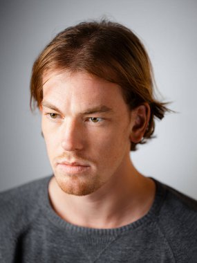 Beyaz bir arka planda, Avrupa görünümlü sarışın bir adamın erkek portresi. Duygular. Ciddi yüz.