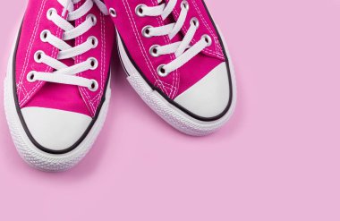 Pembe arka planda fotokopi alanı olan pembe spor ayakkabılar. Gençlik ayakkabıları.