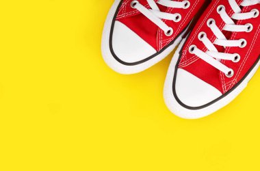 Sarı arka planda kırmızı spor ayakkabılar ve fotokopi alanı. Gençlik ayakkabıları.