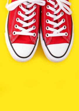 Sarı arka planda kırmızı spor ayakkabılar ve fotokopi alanı. Gençlik ayakkabıları.