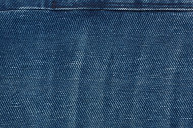 Denim kot desenli yırtık. Renkli pamuk kumaşın dokusu. Dikilmiş desenli kot pantolon. Moda pantolonu düğmesi. Kotun üzerindeki perçin ve cep. İplik ve kumaş yapısı.