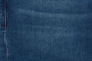 Denim kot desenli yırtık. Renkli pamuk kumaşın dokusu. Dikilmiş desenli kot pantolon. Moda pantolonu düğmesi. Kotun üzerindeki perçin ve cep. İplik ve kumaş yapısı.