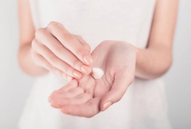 Spa tedavisi. El kremi sürerken kadın ellerini kapat. Kadın elinde krem tüpü tutuyor ve güzel ellerine nemlendirici krem sürüyor. Temiz ve yumuşak cilt için..