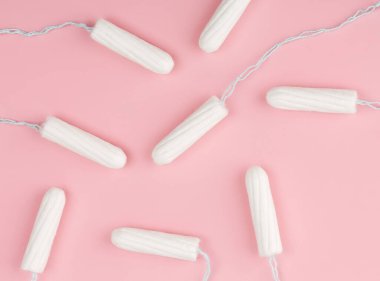 Pembe arka planda tıbbi kadın tamponu. Kadınlar için hijyenik beyaz tampon. Pamuklu çubuk. Regl, korunma aracı. Kırmızı arkaplanda tamponlar.