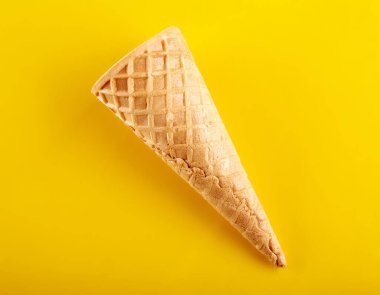 Waffle dondurma külahı sarı arka planda izole edilmiş.