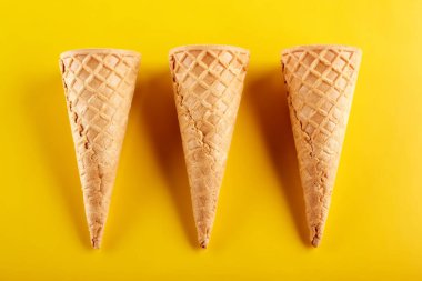 Waffle dondurma külahı sarı arka planda izole edilmiş.