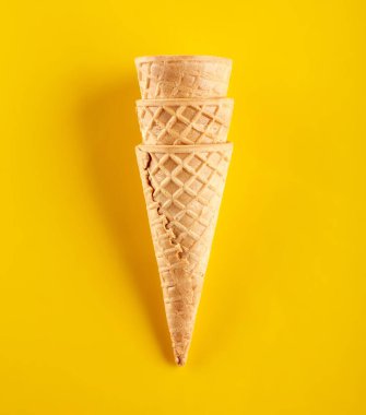 Waffle dondurma külahı sarı arka planda izole edilmiş.