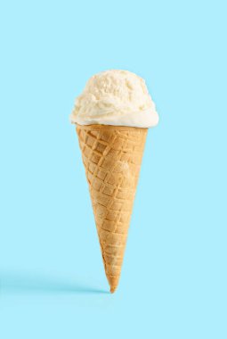 Mavi arka planda waffle külahında beyaz dondurma topu. Waffle külahında meyveli dondurma.