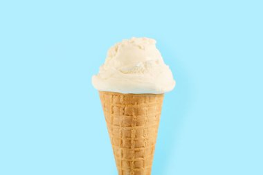 Mavi arka planda waffle külahında beyaz dondurma topu. Waffle külahında meyveli dondurma.