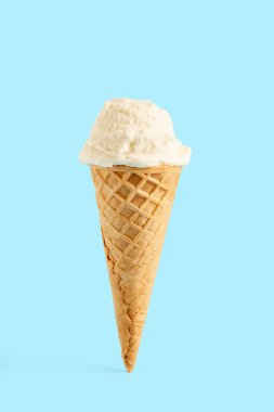 Mavi arka planda waffle külahında beyaz dondurma topu. Waffle külahında meyveli dondurma.