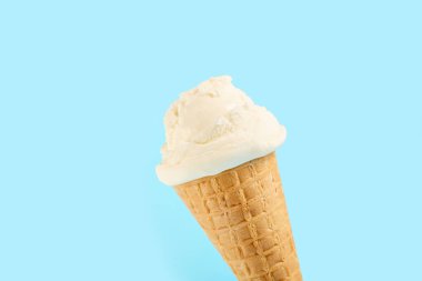 Mavi arka planda waffle külahında beyaz dondurma topu. Waffle külahında meyveli dondurma.