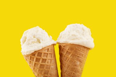 Sarı arka planda, Waffle Cone 'da beyaz dondurma topu. Waffle külahında meyveli dondurma.