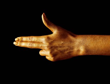 Altın boyalı eller. Altın parmaklar. Ateş eden kadın eli, el hareketi. İzole edilmiş siyah arka planda el tabancası hareketi. İki parmakla işaret eden kadın.