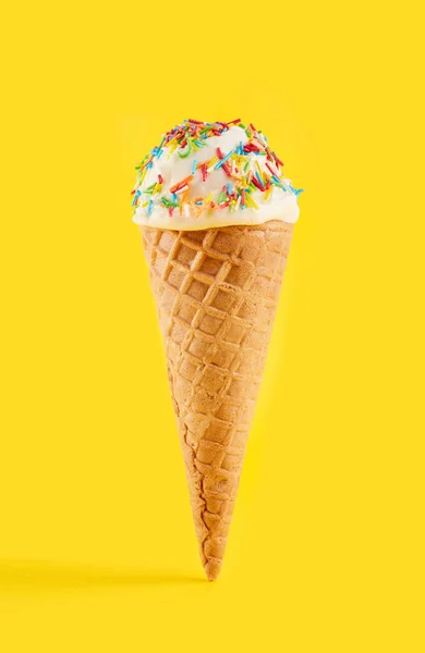 white ice cream ball in a Waffle Cone on a yellow Background. Fruit ice cream in a waffle cone.