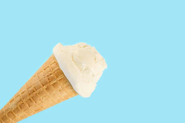 white ice cream ball in a Waffle Cone on a blue Background. Fruit ice cream in a waffle cone.