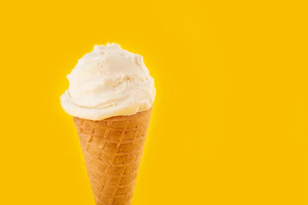 white ice cream ball in a Waffle Cone on a yellow Background. Fruit ice cream in a waffle cone.