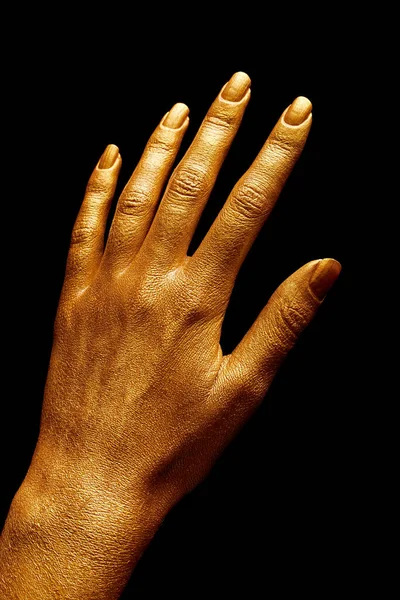 Hands in gold paint. Golden fingers. Female hand isolated on black background. White woman\'s hand showing symbols and gestures.