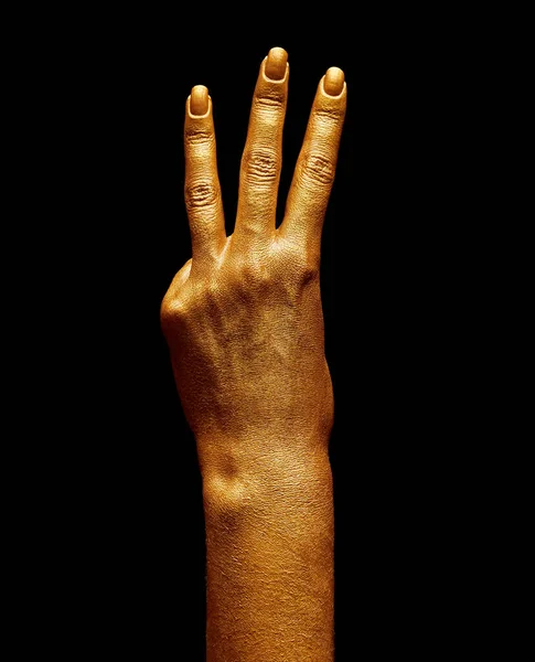 Hands in gold paint. Golden fingers. Female hand is showing numbers isolated on black background. Sign language. Hand numbers