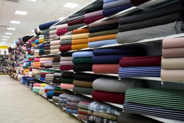 Kumaş mağazasından renkli kumaşlar almak. Renkli kumaşlar indirimde. Fabrika veya mağazada kumaş ve tekstil ruloları. 